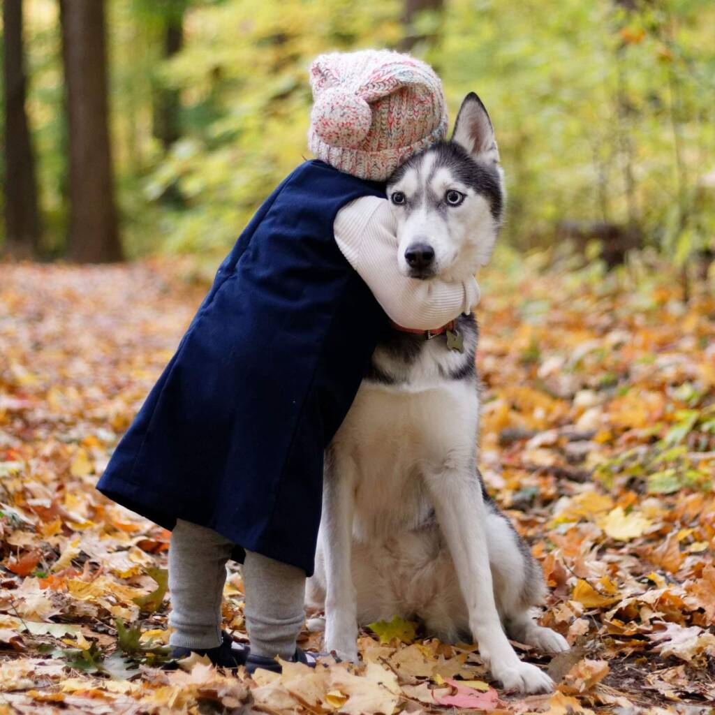 a kid hugging a dog in a jungle